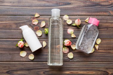 Serum, mikiler, tonik, losyon, gül çiçekli su ve krema için süslü sağlık şişeleri. Doğal orantılı spa kozmetik konsepti. Model, şablon, Üst Görünüm.