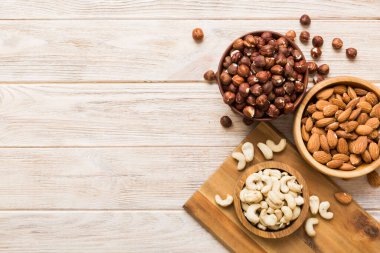 Renkli masadaki ahşap kasede fındık çeşitleri. Ceviz, fındık, ceviz, badem. Fındık Üst görünümü ile kopyalama alanını karıştır.