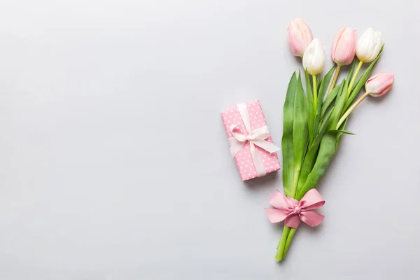 stock image Pink tulips flowers and gift or present box on colored table background. Mothers Day, Birthday, Womens Day, celebration concept. Space for text top view.