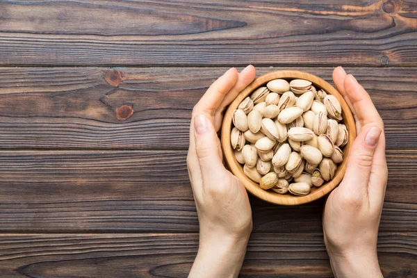 Fıstıklı ahşap bir kase tutan kadın elleri. Sağlıklı yemek ve atıştırmalık. Farklı fındıklı vejetaryen atıştırmalıkları..