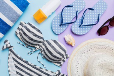 Kadın mayo ve plaj aksesuarları renkli arka plan yaz seyahati konseptine düz bir görünüm kazandırıyordu. Bikini mayo, hasır şapka ve deniz topuklu ayakkabı. Üst görünümü kopyala.