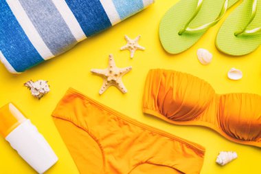 Kadın mayo ve plaj aksesuarları renkli arka plan yaz seyahati konseptine düz bir görünüm kazandırıyordu. Bikini mayo, hasır şapka ve deniz topuklu ayakkabı. Üst görünümü kopyala.