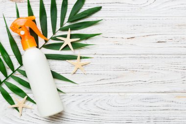 Güneş kremi şişesi. Güneş korumalı krem ve tropik yeşil yapraklı deniz kabukları olan bir şişe..