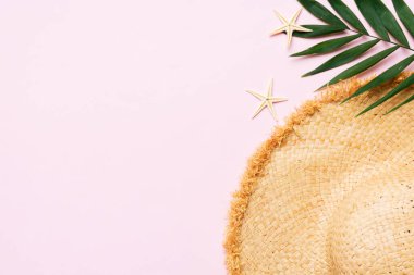 Summer holidays. Summer concept with straw hat and tropical leaf. Flat lay, top view, copy space.
