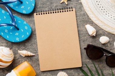 Blank writing book with summer beach accessories on background, copy space. Flat lay with copy space.