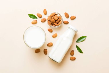 Cam şişedeki badem sütü ve renkli masada badem fıstığı. Üst görünüm vith kopyalama alanı.