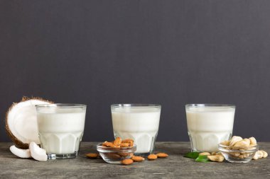 Masa arkasında çeşitli vejetaryen süt bademi, hindistan cevizi, fındık. Vejetaryen bitkisi sütü ve malzemeleri, üst görünüm.