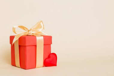 gift box with red bow and red heart on colored background. Perspective view. Flat lay.