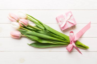 Pembe lale çiçekleri ve hediye ya da renkli masa arkaplanındaki hediye kutusu. Anneler günü, doğum günü, kadınlar günü, kutlama konsepti. Metin üstü görünümü için boşluk.