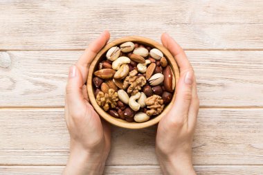 Kadın elleri, fındıklı, fıstıklı, bademli, fındıklı ve fındıklı ahşap bir kase tutuyor. Sağlıklı yemek ve atıştırmalık. Farklı fındıklı vejetaryen atıştırmalıkları..