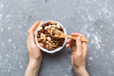 Kadın elleri, fındıklı, fıstıklı, bademli, fındıklı ve fındıklı ahşap bir kase tutuyor. Sağlıklı yemek ve atıştırmalık. Farklı fındıklı vejetaryen atıştırmalıkları..