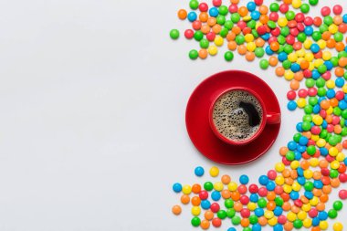 Coffee cup with chocolates and colored candy. Top view on table background with copy space.