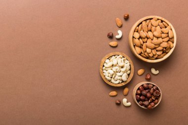 Renkli masadaki ahşap kasede fındık çeşitleri. Ceviz, fındık, ceviz, badem. Fındık Üst görünümü ile kopyalama alanını karıştır.