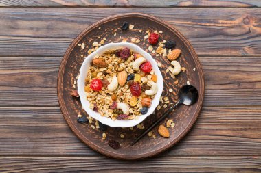 Sağlıklı bir kahvaltı hazırlıyorum. Bir kasede çeşitli kurutulmuş meyve ve fındıklı granola. Sağlıklı tatlı kavramı. Düz konum, kopyalama alanı olan üst görünüm.