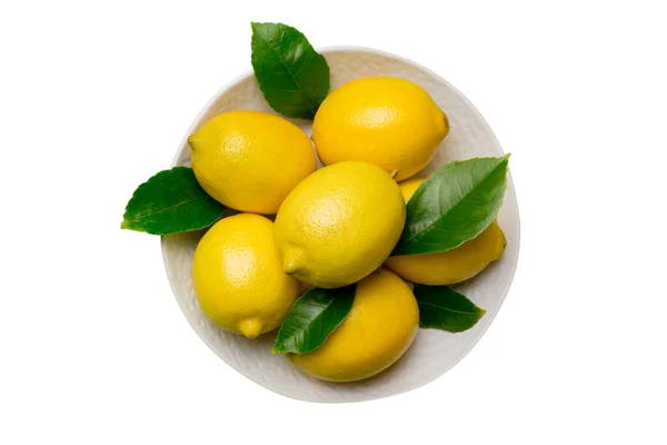 Frisch Geschnittene Zitrone Und Ganze Zitronen Auf Rundem Teller Isoliert — Stockfoto