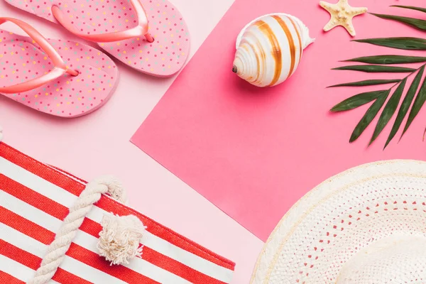 Beach accessories straw hat and seashell on colored table. Summer concept background.