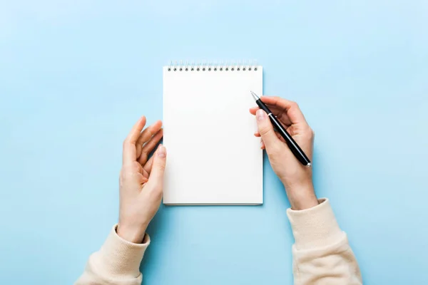 Woman hand with pencil writing on notebook. Woman working on office table. Female hand holding pencil and sketchbook. Mock-up Concept.