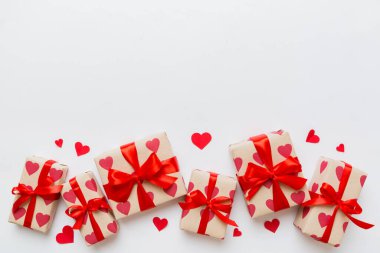 Top view photo of valentine day decorations gift box with red ribbon bow on colored background. Holiday gift boxes with top view.