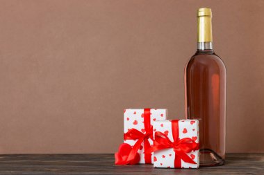 Bottle of wine on colored background for Valentine Day with gift box. Heart shaped with presrnt box perspective view with copy space.