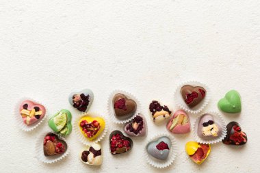 chocolate sweets in the form of a heart with fruits and nuts on a colored background. top view with space for text, holiday concept.