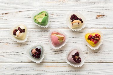 chocolate sweets in the form of a heart with fruits and nuts on a colored background. top view with space for text, holiday concept.