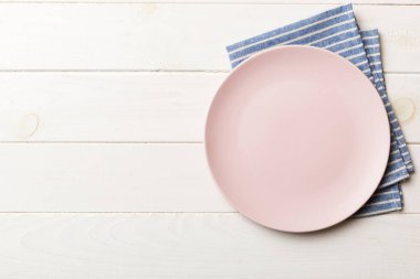 Renkli arka planda üst manzara. Yemek için masa örtüsü üzerine yuvarlak pembe tabak. Tasarımınız için boşluk olan peçeteye boş tabak.