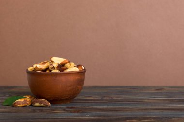 Fresh healthy Brazil nuts in bowl on colored table background. Top view Healthy eating bertholletia concept. Super foods.