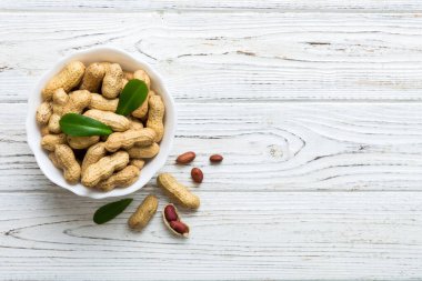 Fresh healthy peanuts in bowl on colored table background. Top view Healthy eating bertholletia concept. Super foods.