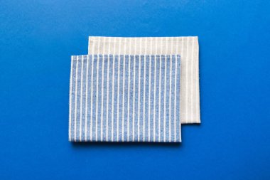 top view with blue kitchen napkin isolated on table background. Folded cloth for mockup with copy space, Flat lay. Minimal style.
