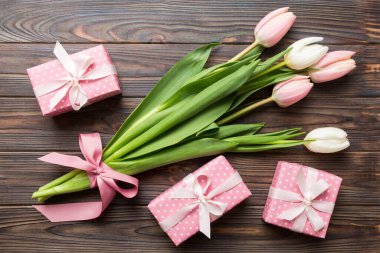 Pembe lale çiçekleri ve hediye ya da renkli masa arkaplanındaki hediye kutusu. Anneler günü, doğum günü, kadınlar günü, kutlama konsepti. Metin üstü görünümü için boşluk.