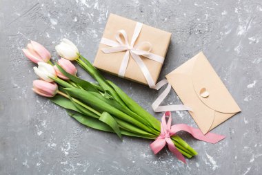 Pembe lale çiçekleri ve hediye ya da renkli masa arkaplanındaki hediye kutusu. Anneler günü, doğum günü, kadınlar günü, kutlama konsepti. Metin üstü görünümü için boşluk.