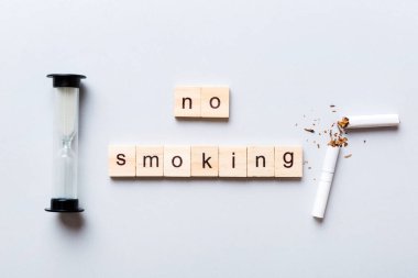 Sigara ve ahşap bloklar, masa arkasında kum saati ile kırılmış sigara kum saati ile tütün günü yok, saat sağlığı konsepti. Sigarayı bırakma zamanı..