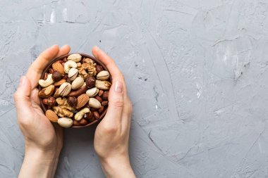 Kadın elleri, fındıklı, fıstıklı, bademli, fındıklı ve fındıklı ahşap bir kase tutuyor. Sağlıklı yemek ve atıştırmalık. Farklı fındıklı vejetaryen atıştırmalıkları..