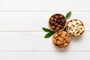 Renkli masadaki ahşap kasede fındık çeşitleri. Ceviz, fındık, ceviz, badem. Fındık Üst görünümü ile kopyalama alanını karıştır.