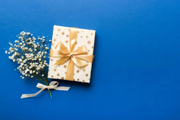 Gift or present box and flower gypsophila on light table top view. Greeting card. Flat lay style with copy space.