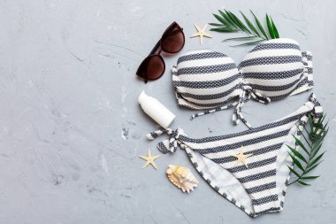 Woman swimwear and beach accessories flat lay top view on colored background Summer travel concept. bikini swimsuit, straw hat and seasheels. Copy space Top view.