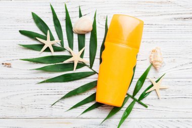 Güneş kremi şişesi. Güneş korumalı krem ve tropik yeşil yapraklı deniz kabukları olan bir şişe..