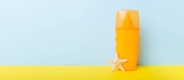 Plaj aksesuarları. Yazın UVB cilt koruması için nemlendirici güneş kremi şişesi ve renkli arka planda deniz kabukları. Kopyalama alanı kullan.