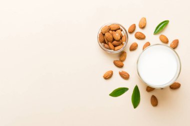 Cam şişedeki badem sütü ve renkli masada badem fıstığı. Üst görünüm vith kopyalama alanı.