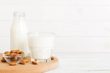 Cam şişedeki badem sütü ve renkli masada badem fıstığı. Üst görünüm vith kopyalama alanı.