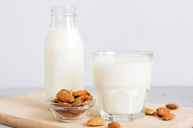 Cam şişedeki badem sütü ve renkli masada badem fıstığı. Üst görünüm vith kopyalama alanı.