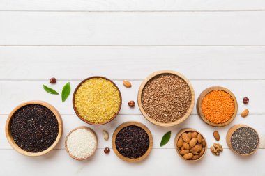 Smal Bowl 'da renkli arka planda çeşitli süper yiyecekler. Pirinç, chia, kinoa, mercimek, fındık, susam tohumu, badem gibi süper yiyecekler. üst görünüm kopyalama alanı.