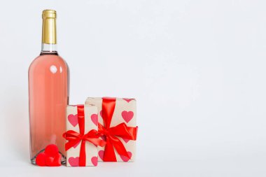 Bottle of wine on colored background for Valentine Day with gift box. Heart shaped with presrnt box perspective view with copy space.