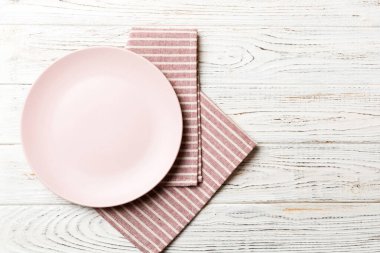 Renkli arka planda üst manzara. Yemek için masa örtüsü üzerine yuvarlak pembe tabak. Tasarımınız için boşluk olan peçeteye boş tabak.