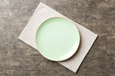 Renkli arka planda üst görünüm yiyecek için masa örtüsünün üzerinde boş yuvarlak yeşil tabak. Tasarımınız için boşluk olan peçeteye boş tabak.