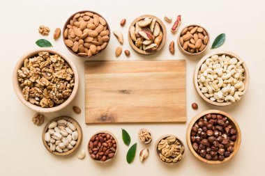 mixed nuts in wooden bowl. Mix of various nuts on colored background. pistachios, cashews, walnuts, hazelnuts, peanuts and brazil nuts.