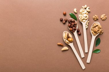 mixed nuts in white wooden spoon. Mix of various nuts on colored background. pistachios, cashews, walnuts, hazelnuts, peanuts and brazil nuts.