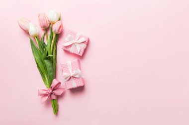 Pembe lale çiçekleri ve hediye ya da renkli masa arkaplanındaki hediye kutusu. Anneler günü, doğum günü, kadınlar günü, kutlama konsepti. Metin üstü görünümü için boşluk.
