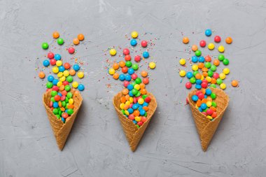 waffle cone full of assorted traditional candies falling out on colored background with copy space. Happy Holidays sale concept.