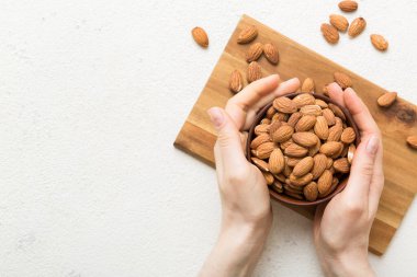 Kadın elleri, badem fıstıklı ahşap bir kase tutuyor. Sağlıklı yemek ve atıştırmalık. Farklı fındıklı vejetaryen atıştırmalıkları..